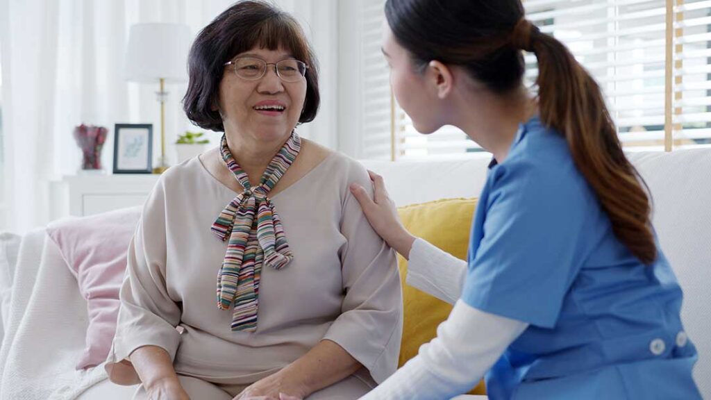 Older adult reviewing care documents with a family member at a kitchen table.